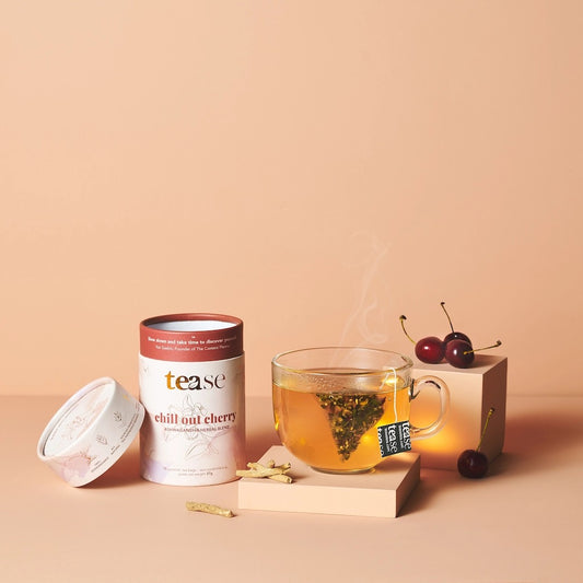 Tea canister labeled 'tease' with a glass of tea and cherry decorations on a beige background