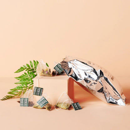 Tease Tea bags with a metallic bag on a beige background