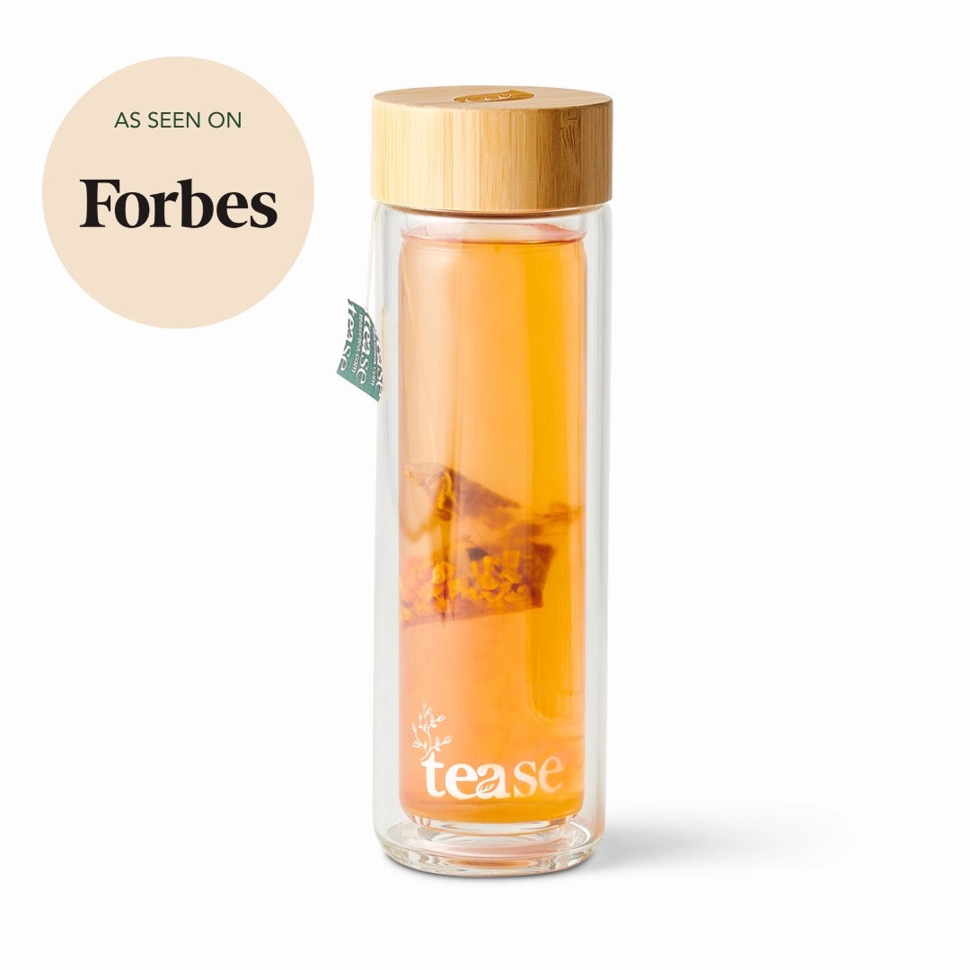 Tease Glass tea bottle with bamboo lid containing orange tea, branded 'Tease', on a white background.
