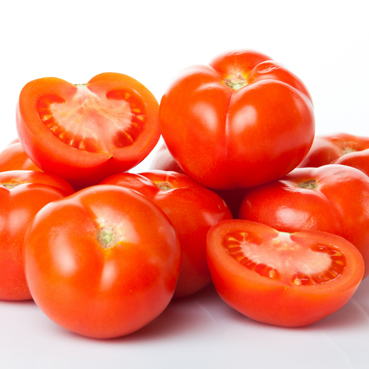 a pile of bright red whopping red tomatoes with two halves against a white background