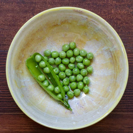 a white bowl holding green Alaska shelling peas