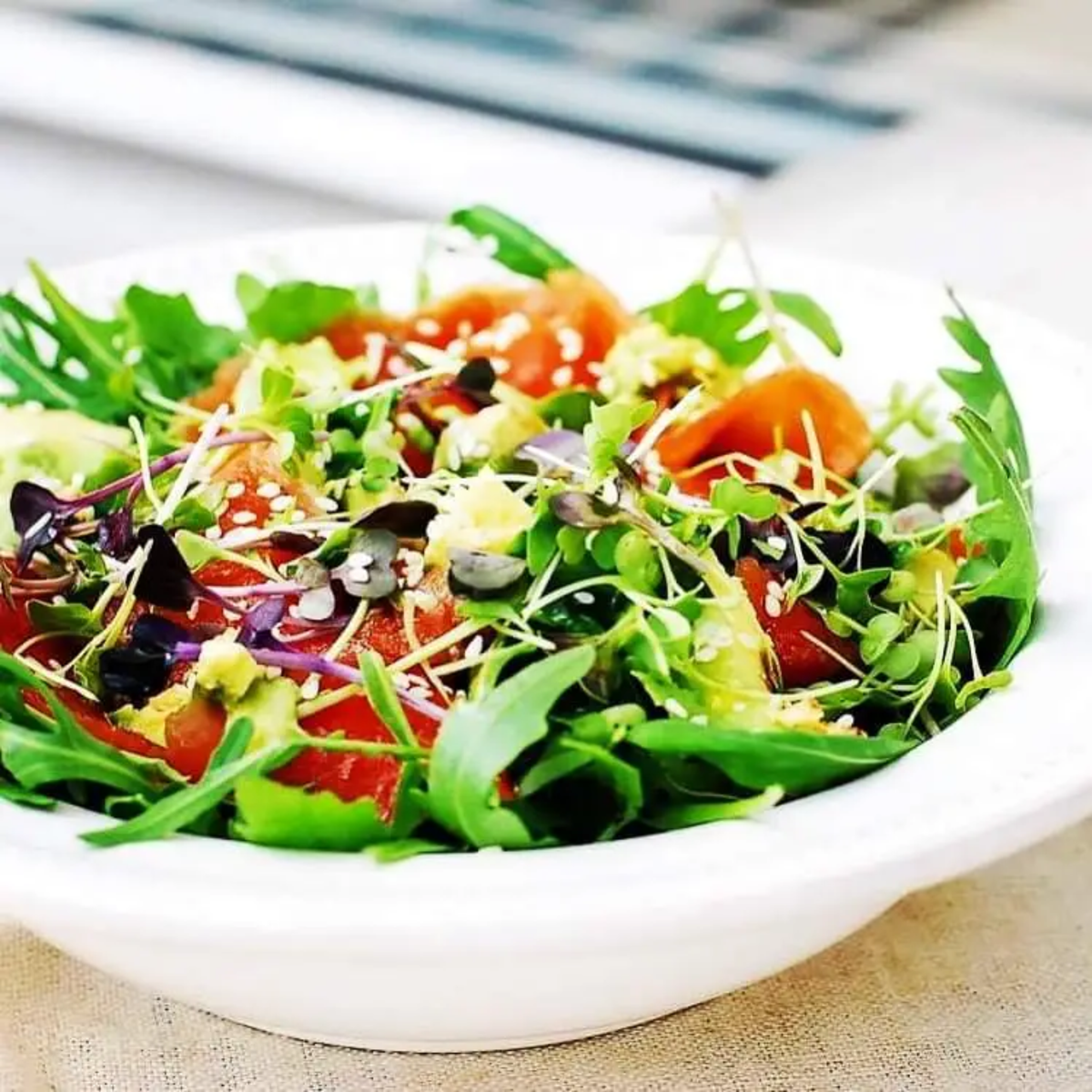 a colourful salad containing alfalfa micro greens in a white bowl with a soft blurred background