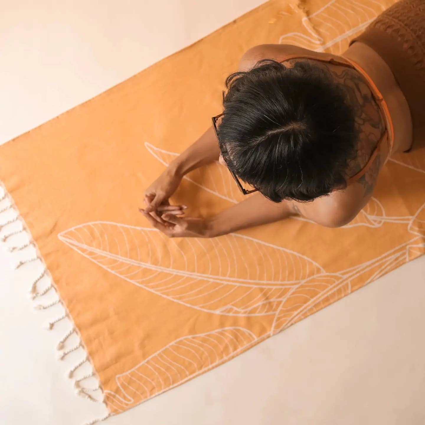 a person laying on an orange beach towel