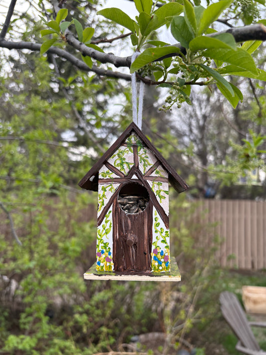 a small painted birdhouse hanging in a tree