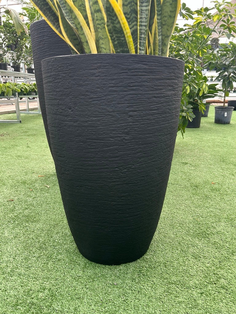 a modern black planter on a grass like surface
