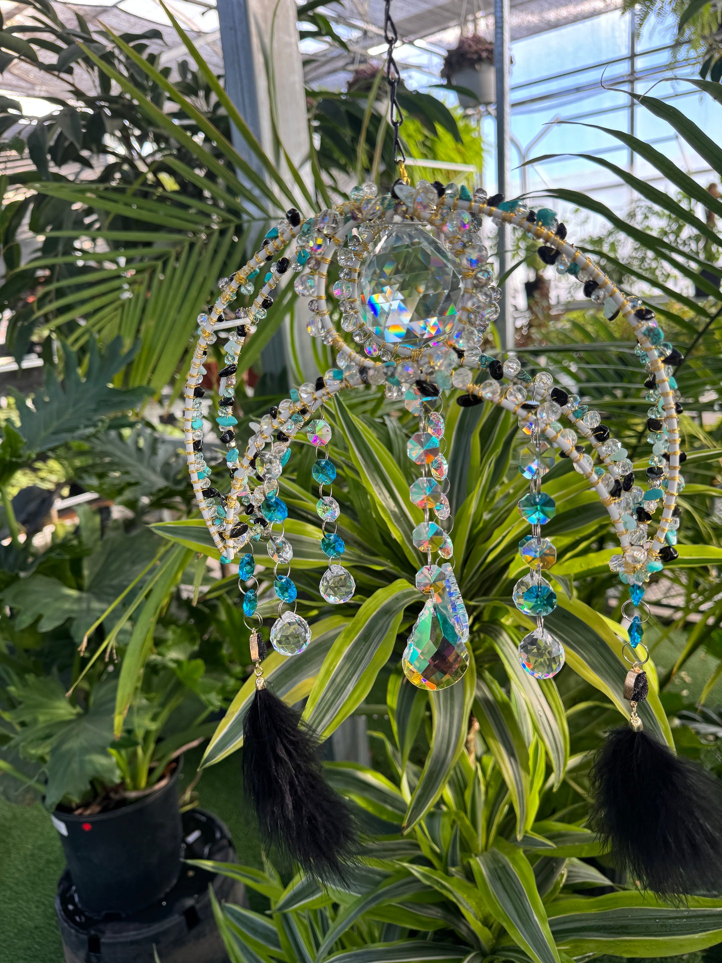 decorative umbrella sun catcher with blue white and black beading and black feathers hanging from each end