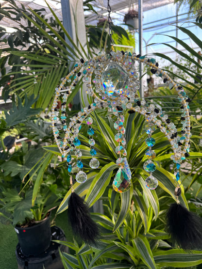 decorative umbrella sun catcher with blue white and black beading and black feathers hanging from each end