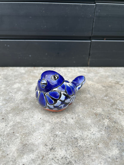 a ceramic blue bird pot holder resting on a concrete surface