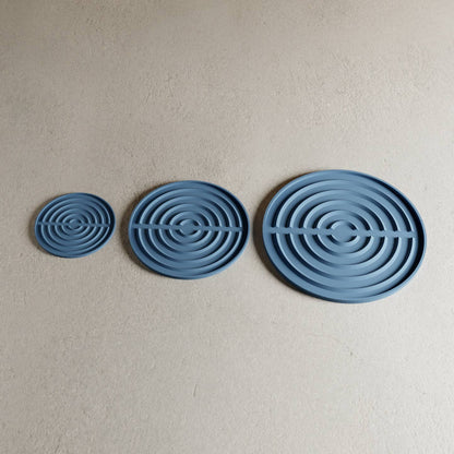 three blue puddle saucers of various sizes against a plain background