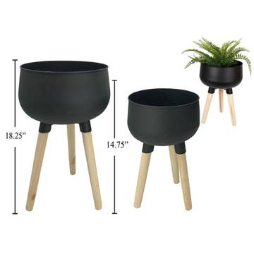 Two black metal planters with wood legs, one large and one small, displayed with a plant inside the larger one. The planters are shown from different angles, showcasing the sizes and the design.