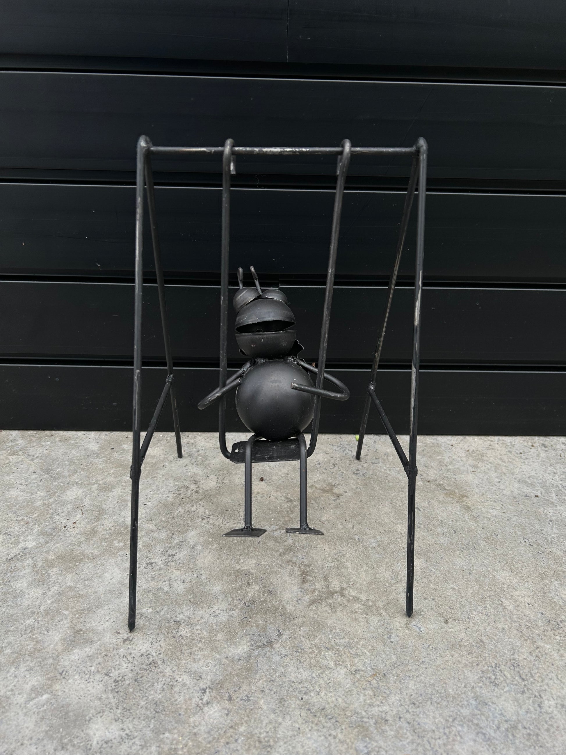 a black metal bug on a black metal swing