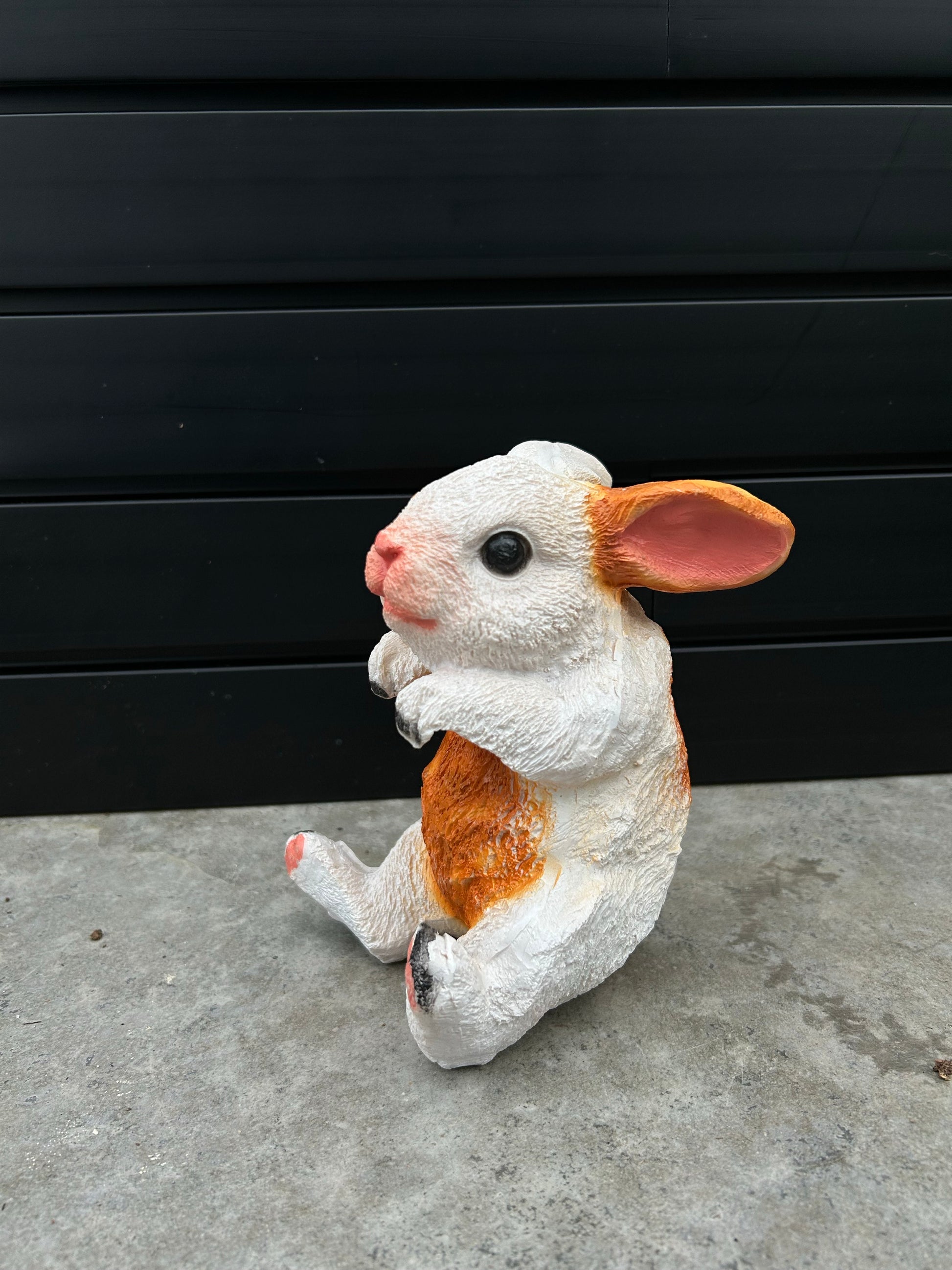 a ceramic white and brown bunny with its arms shaped perfectly to hold a pot