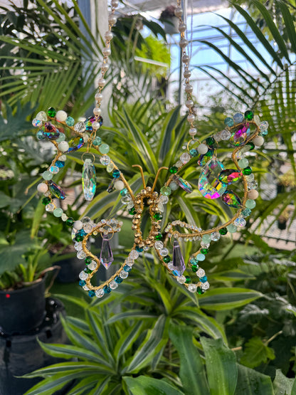 decorative butterfly sun catcher with sparkling dangling crystals surrounded by plants