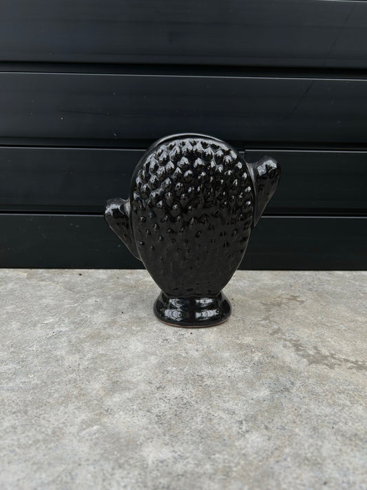 shiny black ceramic pot shaped like a cactus on concrete floor a=with black background