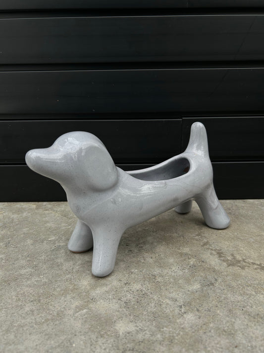 gray ceramic dog planter pot on concrete floor with black background
