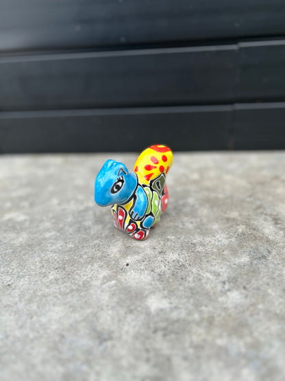 a brightly coloured and patterned ceramic squirrel on a concrete surface