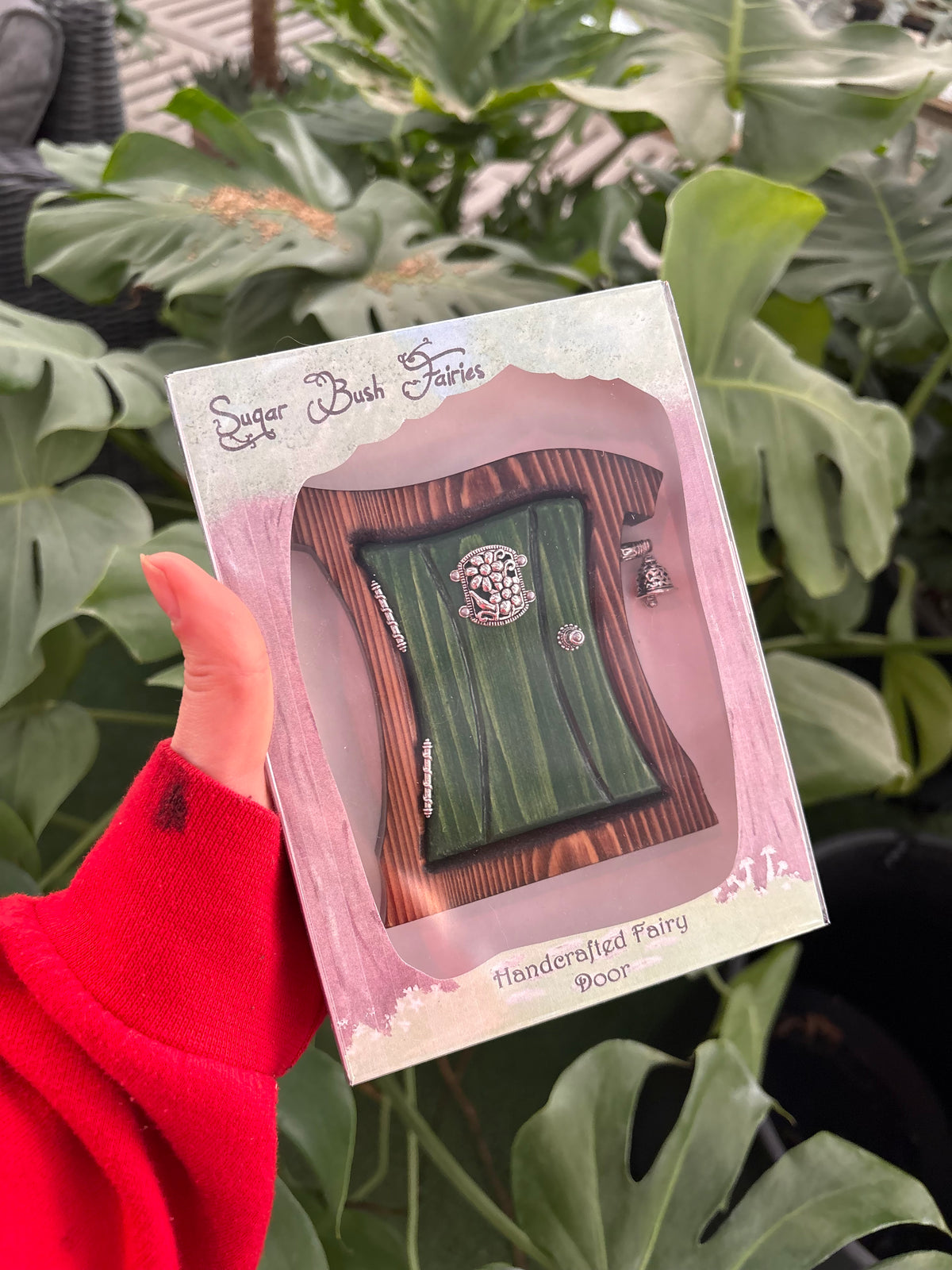 green fairy door with wood and silver accents surrounded by plants