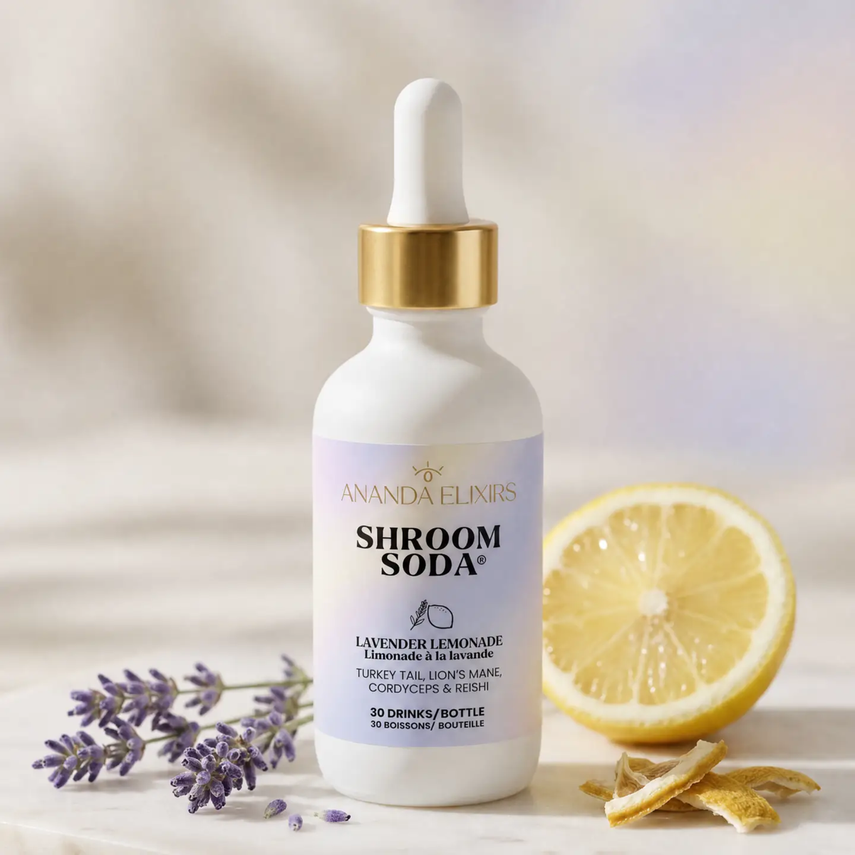 a white dropper bottle with a pale purple label that reads shroom soda lavender lemonade with a sprig of lavender and half a lemon resting beside the bottle and a white background