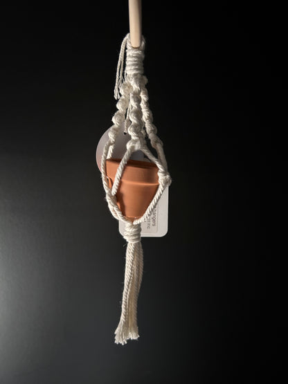 a mini macrame plant hanger holding a small pot