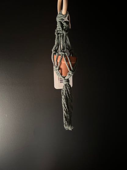a green mini macrame plant hanger holding a small pot