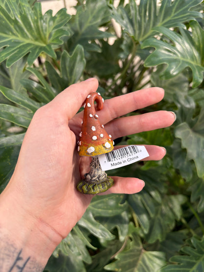 Hand holding a small mini toadstool  with a barcode label against a green leafy background