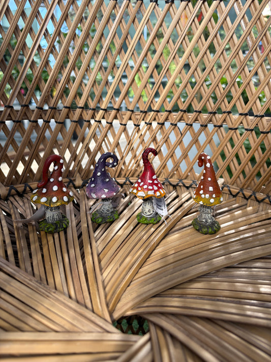 four decorative mini toad stools in different colours sitting on a wicker surface