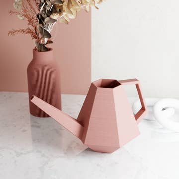 a pink watering can on a marble surface