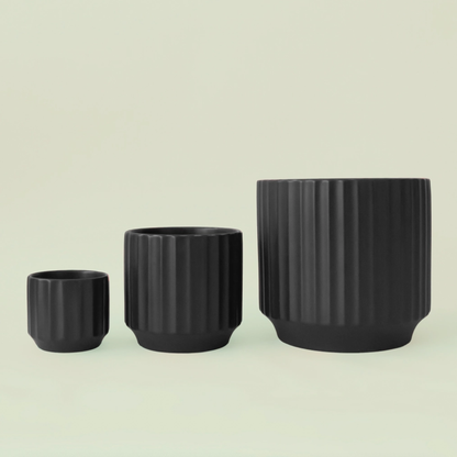 three black ceramic planters of different sizes all lined up against a white background