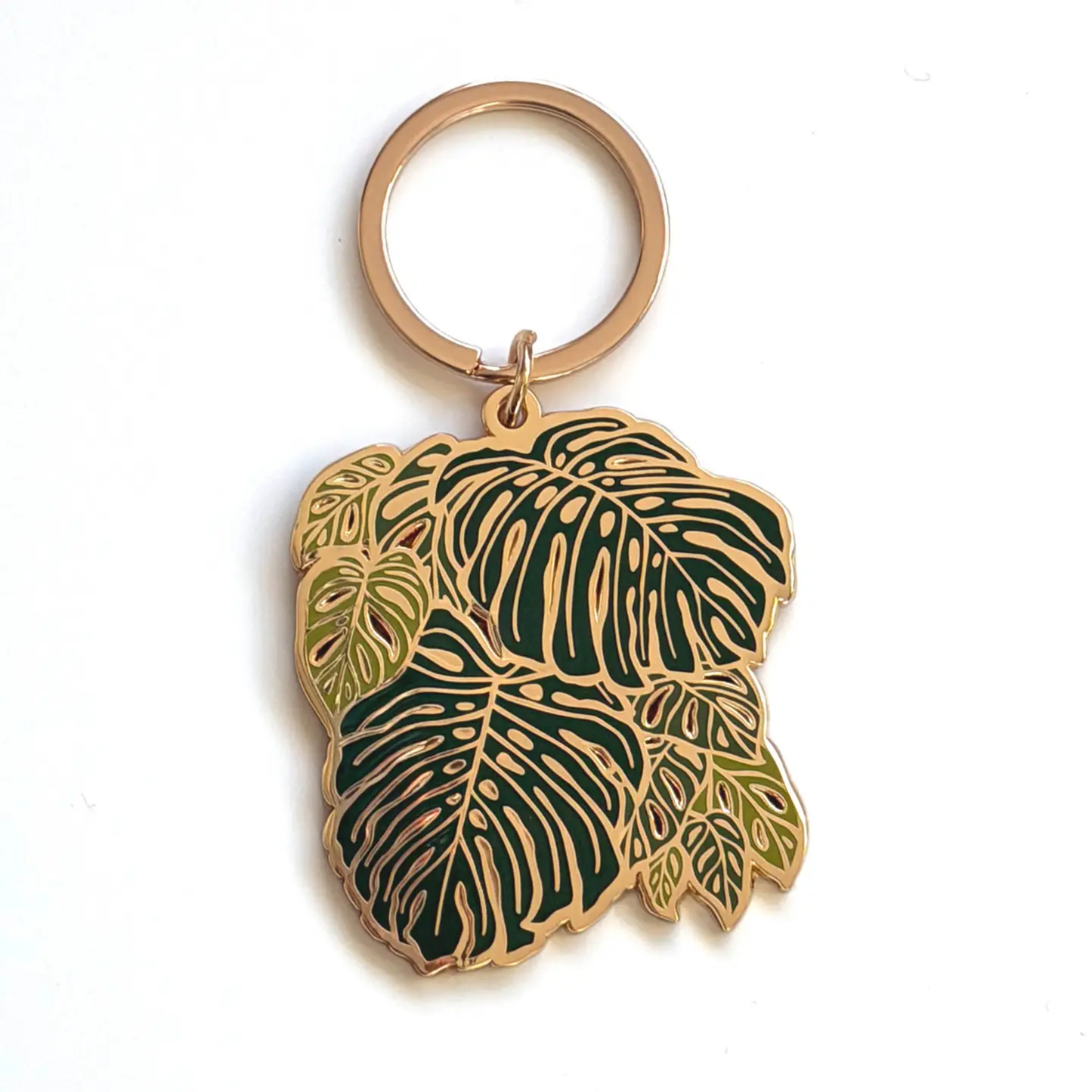 a gold keychain with a monstera plant leaf design on a white background