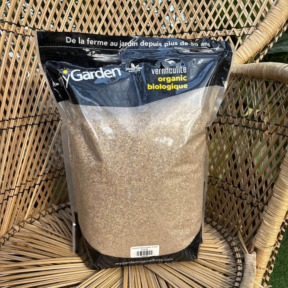 a bag with a black top that reads my garden vermiculite organic with the rest of the bag being see through showing the sand like vermiculite insides with the bag resting on a wicker chair
