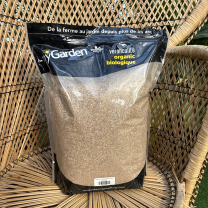 a bag with a black top that reads my garden vermiculite organic with the rest of the bag being see through showing the sand like vermiculite insides with the bag resting on a wicker chair