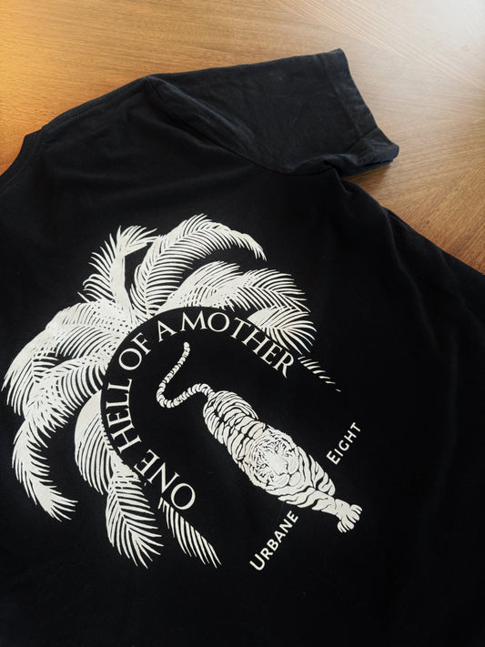 Black t-shirt with a white graphic of a tiger and palm trees, and text reading 'One Hell of a Mother' and 'Urban Eight'.