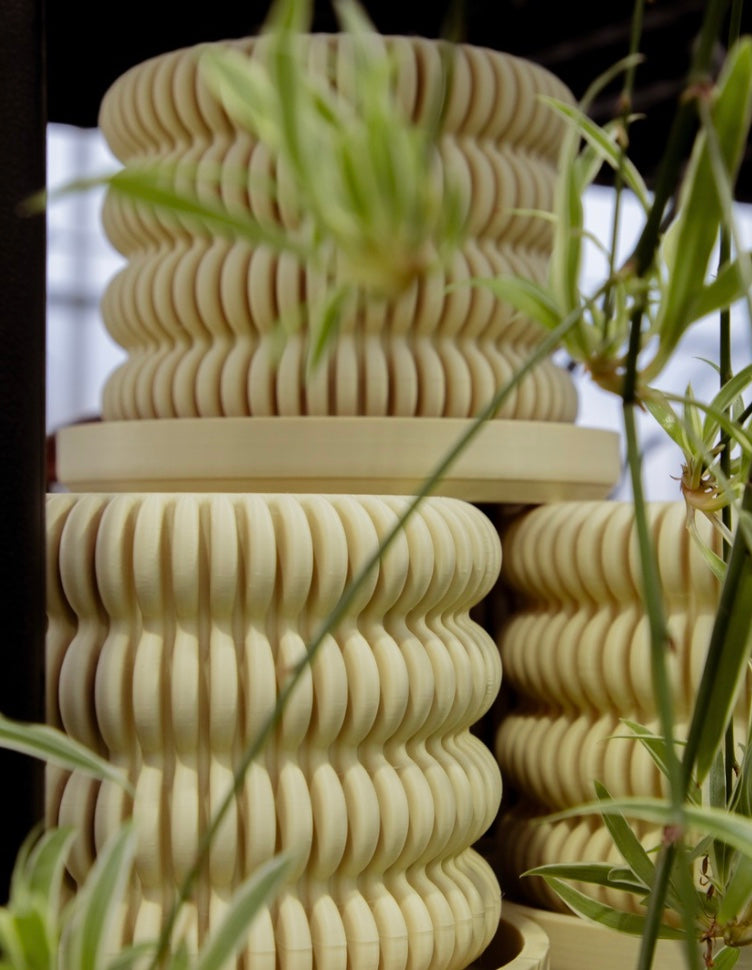 a stack of textured pagoda pots surrounded by plants