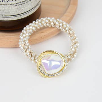 a pearl scrunchie with a larger central pearl resting on a table