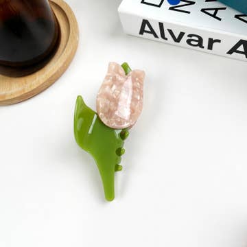 a tulip shaped pink and green hair clip against a white background