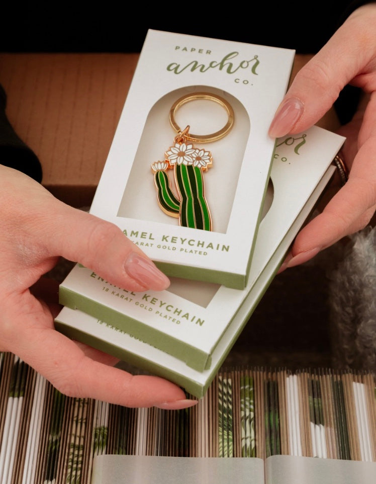 hands holding cactus shaped plant keychains