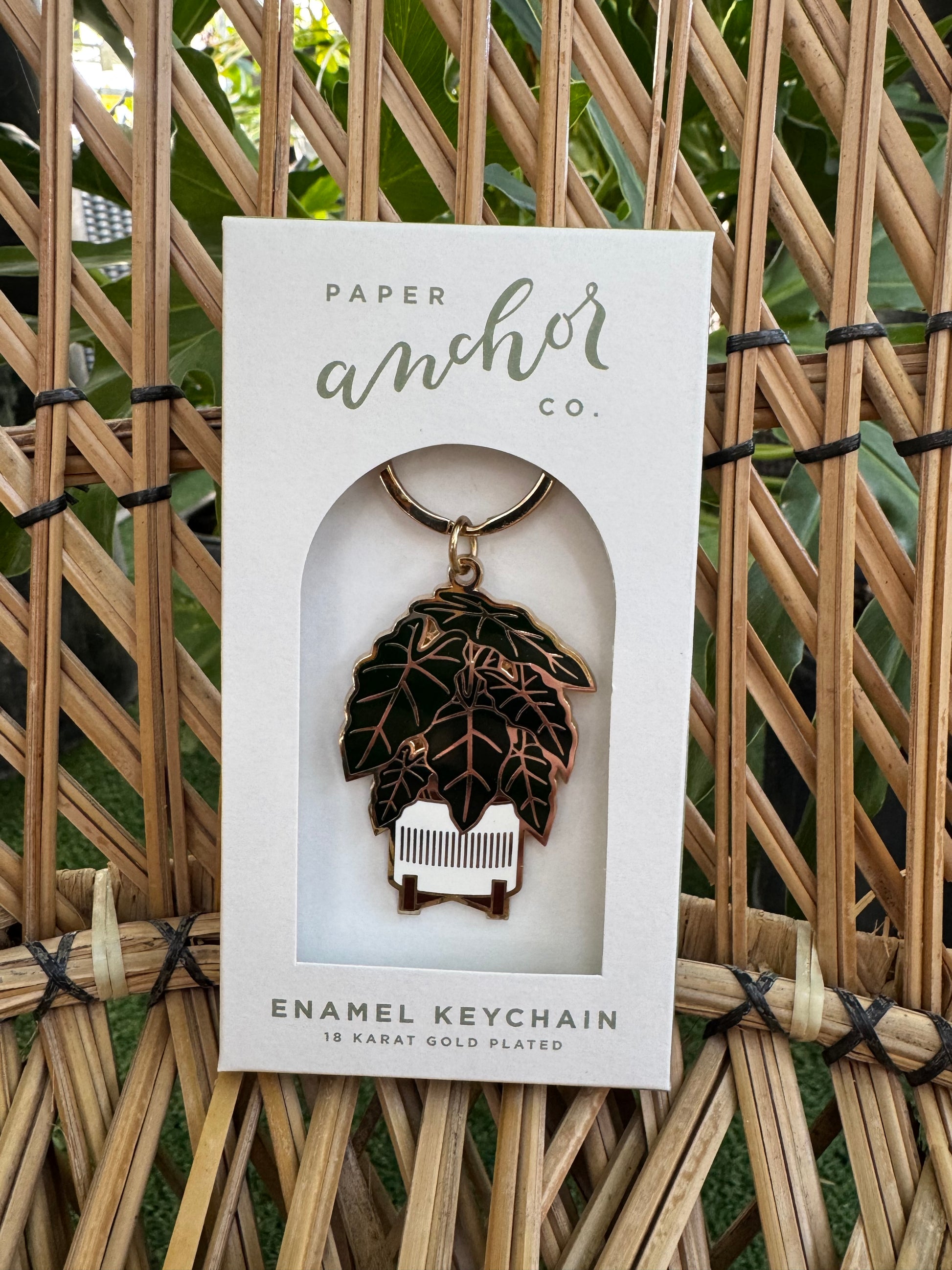 Enamel plant themed keychain in packaging on a woven surface