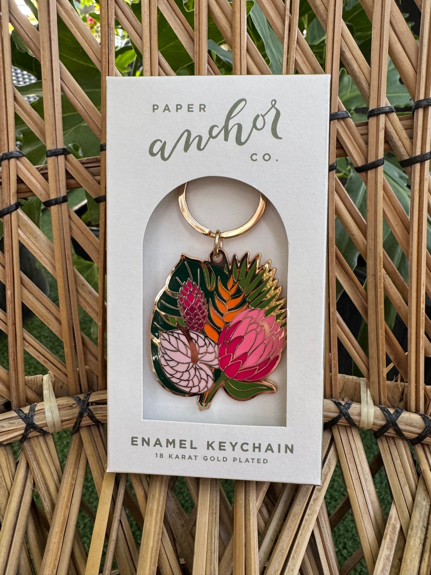 Enamel keychain with floral design in a Paper packaging on a woven background
