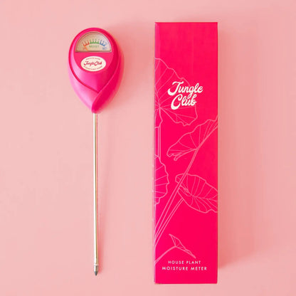 a bright pink moisture meter resting next to a pink box with the logo jungle club against  pale pink background