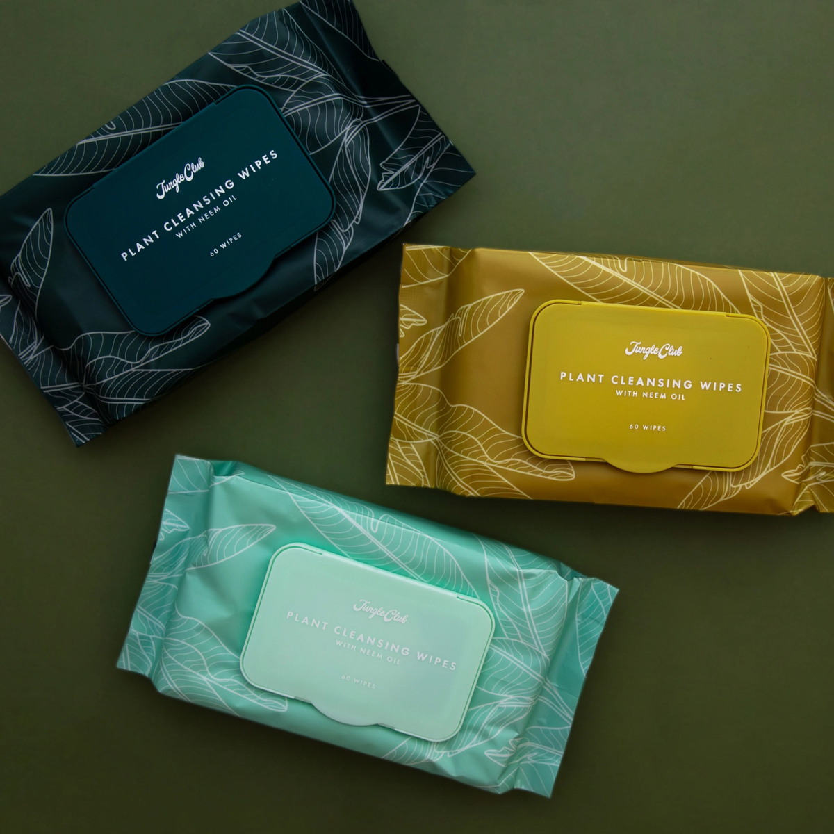 three packages in yellow dark green and tan of plant cleansing wipes against a green background