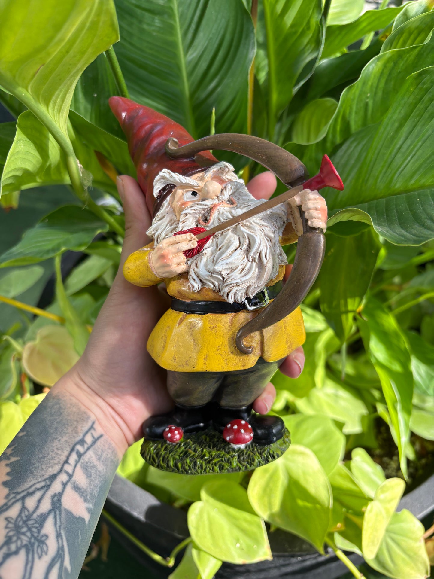 Hand holding a small gnome figurine with a green leafy background