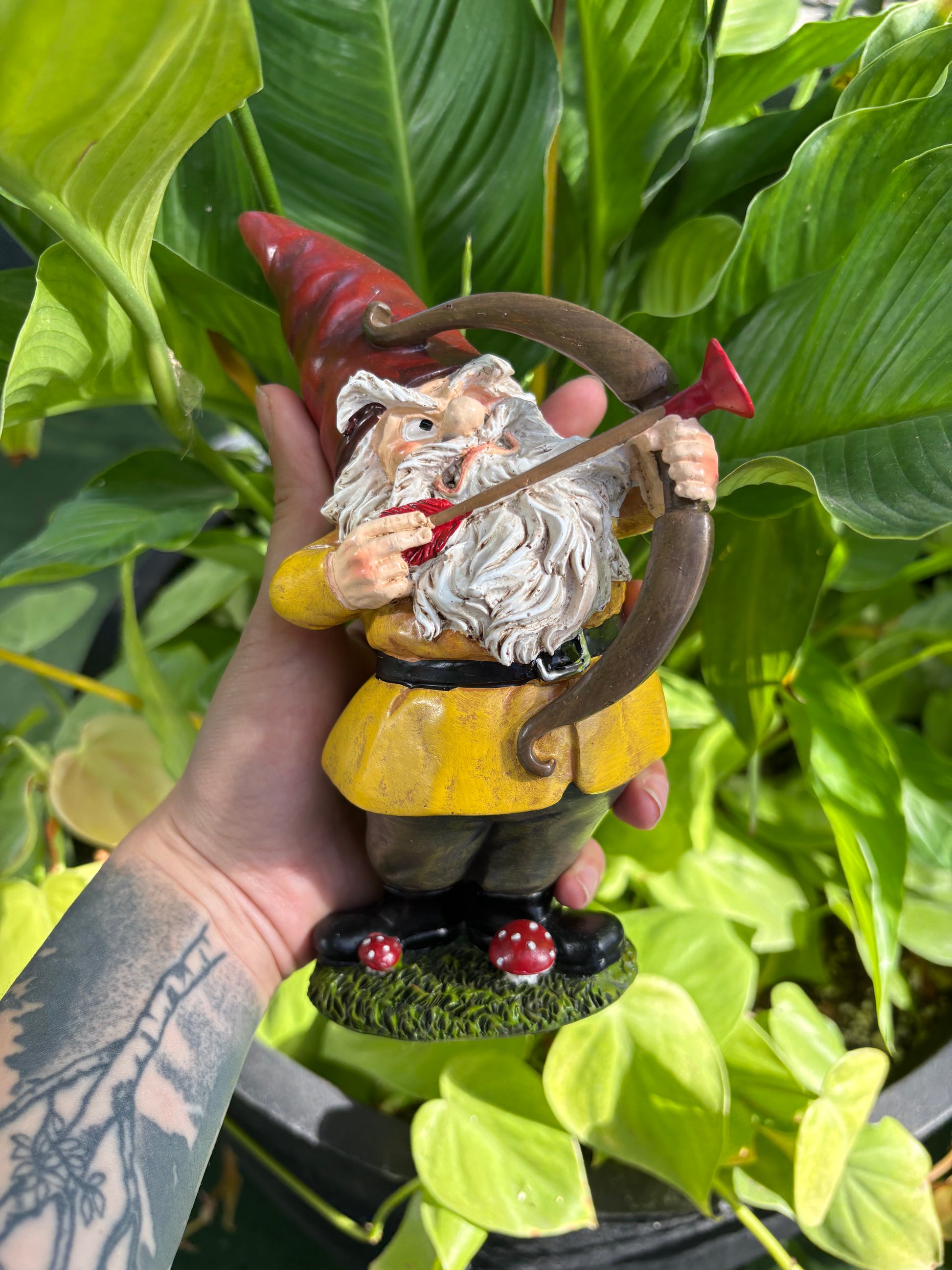 Hand holding a small gnome figurine with a green leafy background