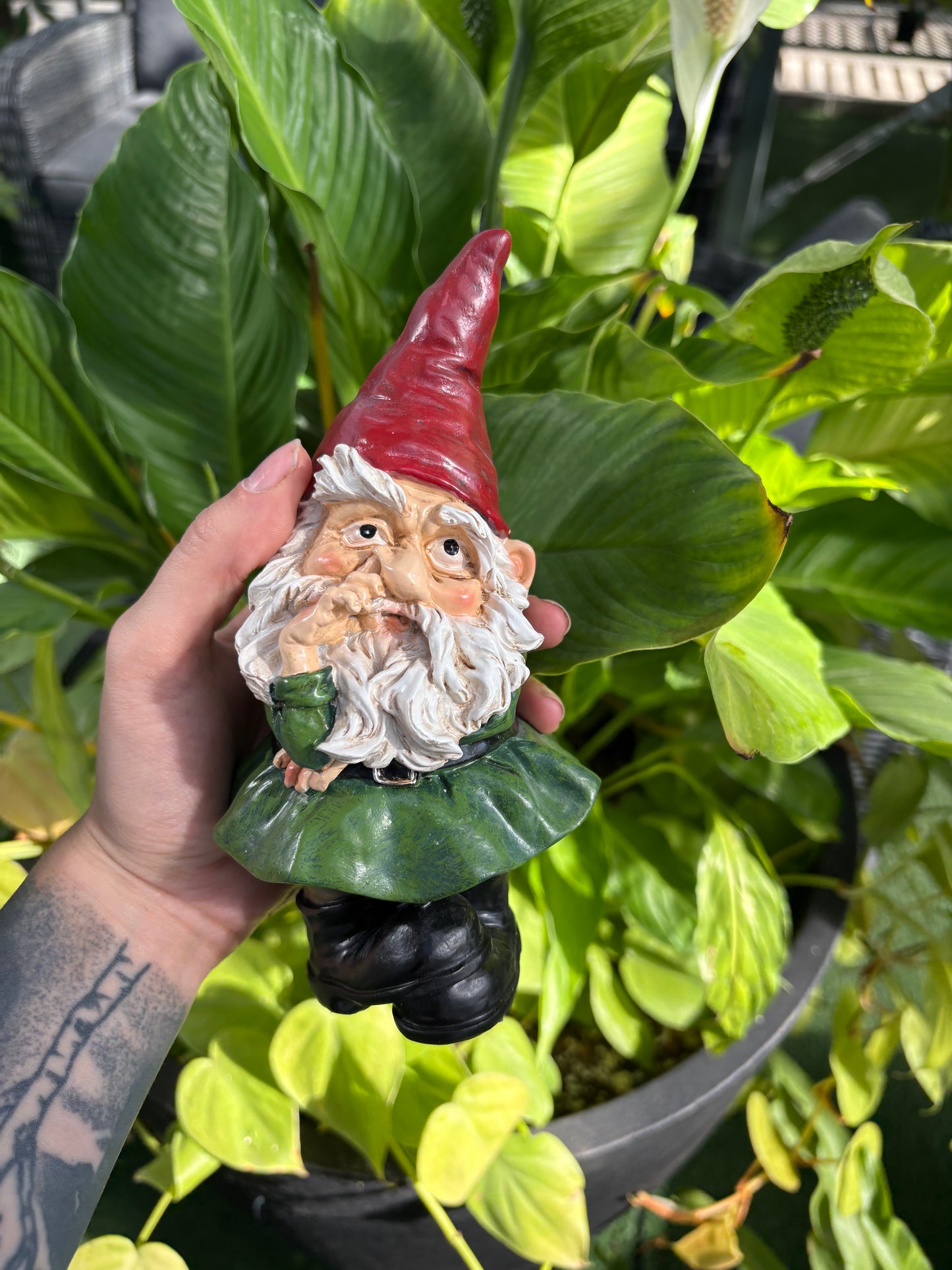Gnome figurine held by a hand with green leaves in the background