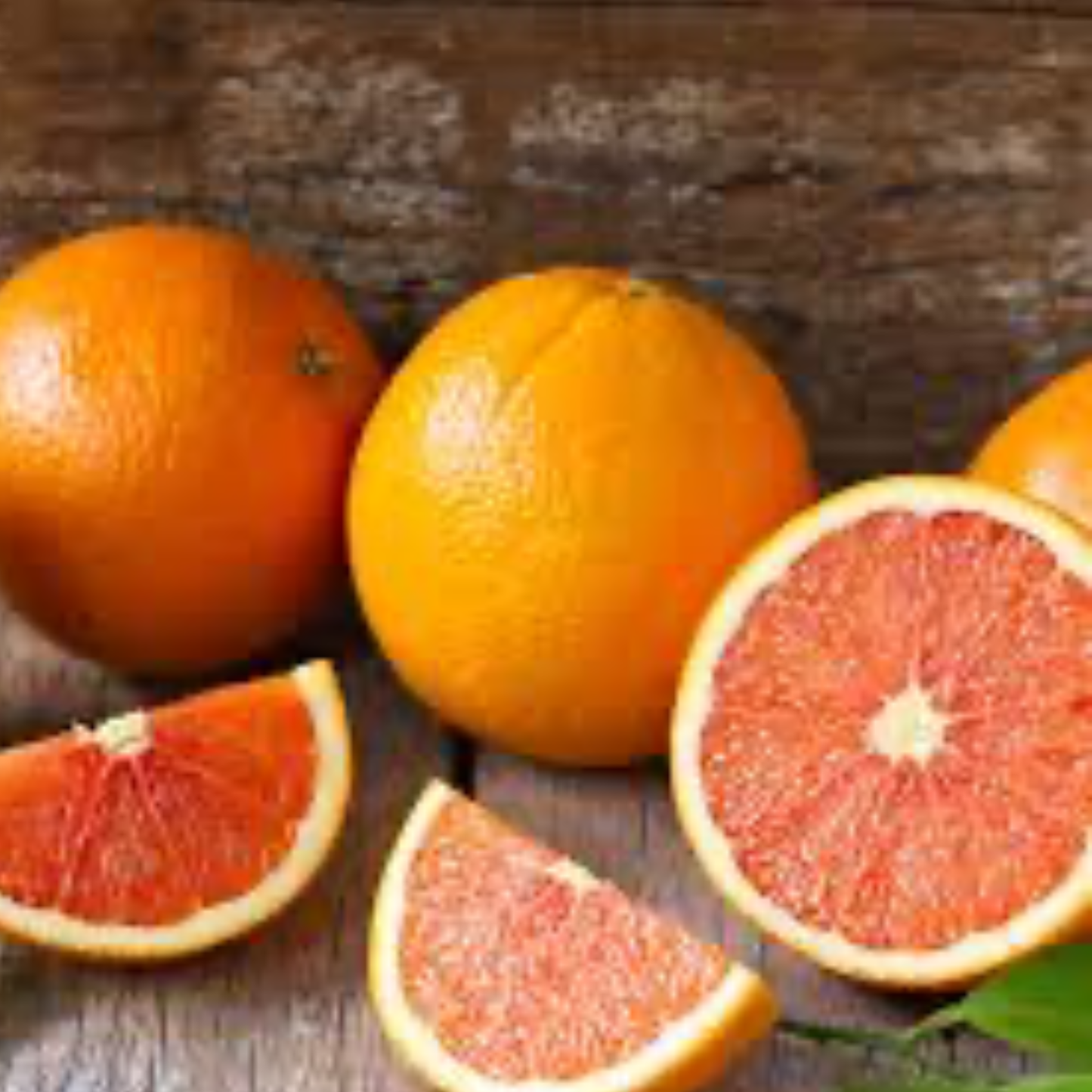 a collection of whole and cut up red navel oranges with a wooden background