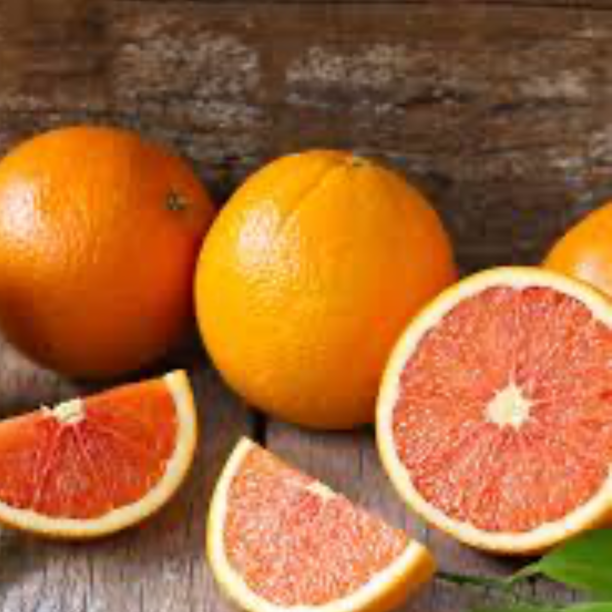 a collection of whole and cut up red navel oranges with a wooden background