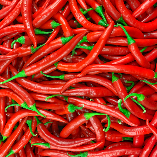 a large pile of bright red ring of fire peppers with green stems