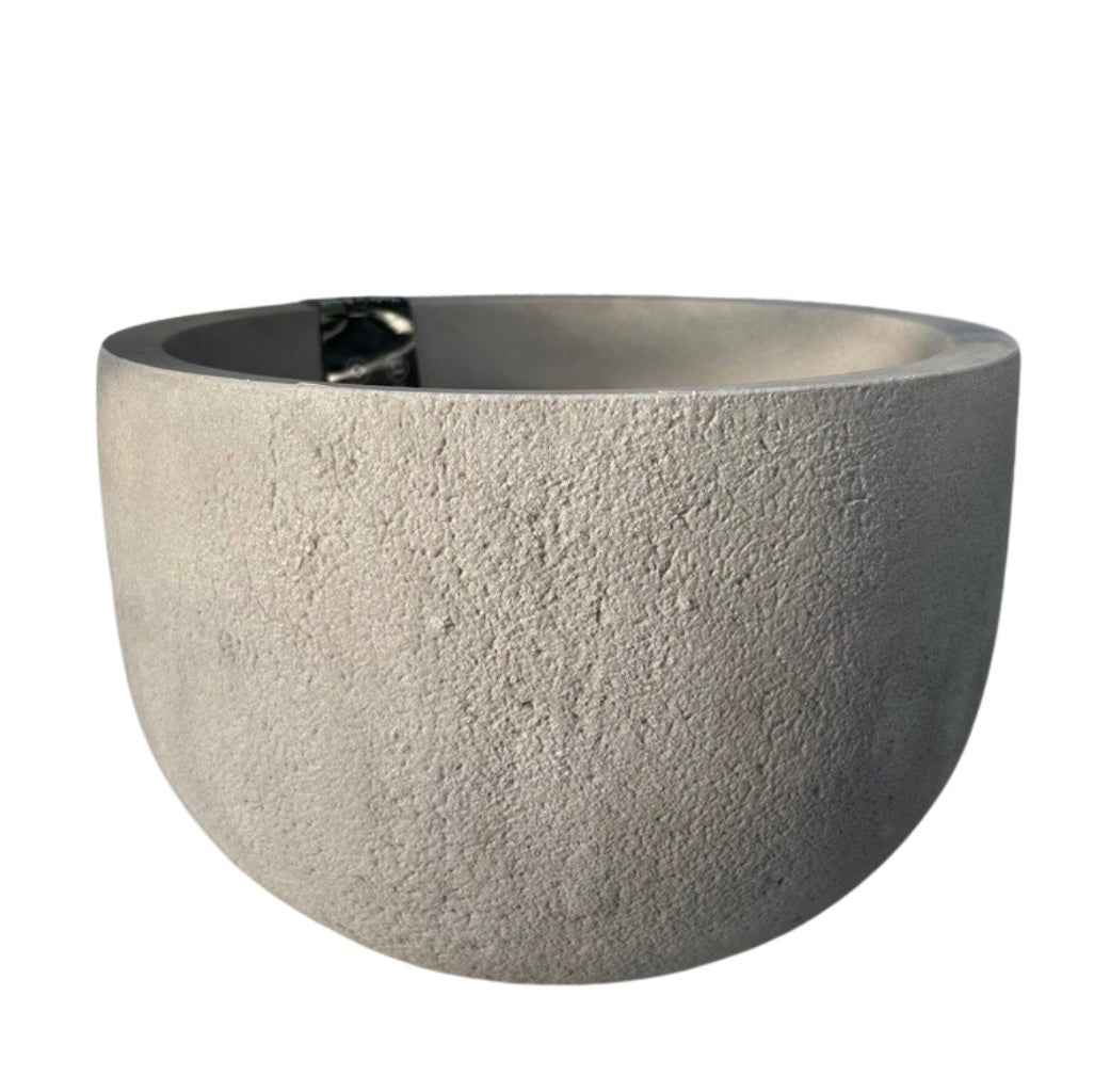 A rustic round planter made of concrete with a burnt cement finish.