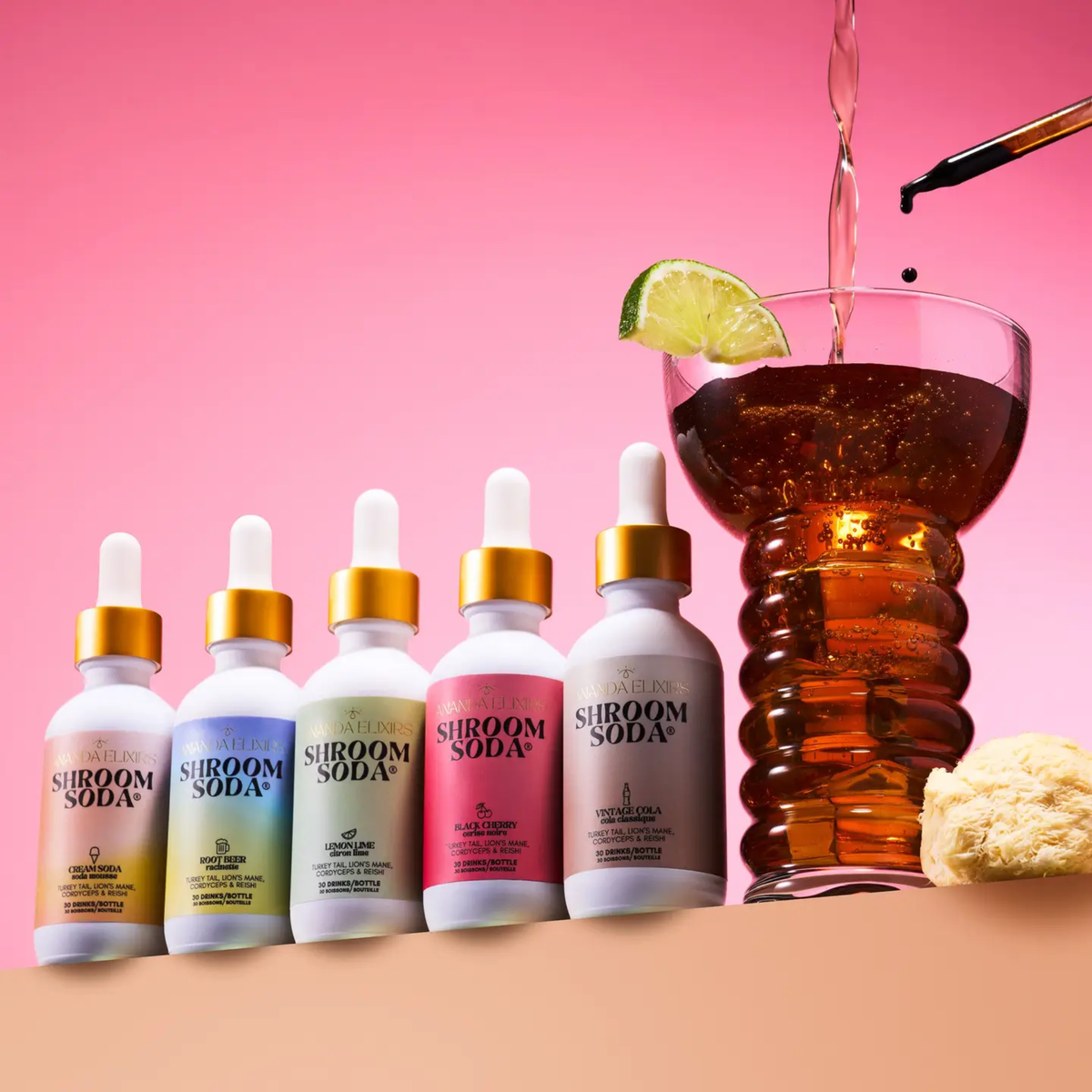 five different white dropper bottles all with different coloured labels all reading shroom soda next to a glass of soda with a pink background