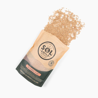 a tan bag of sol soils calcined clay with its sand like contents spilled onto the white background