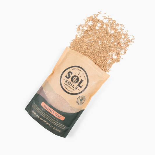 a tan bag of sol soils calcined clay with its sand like contents spilled onto the white background